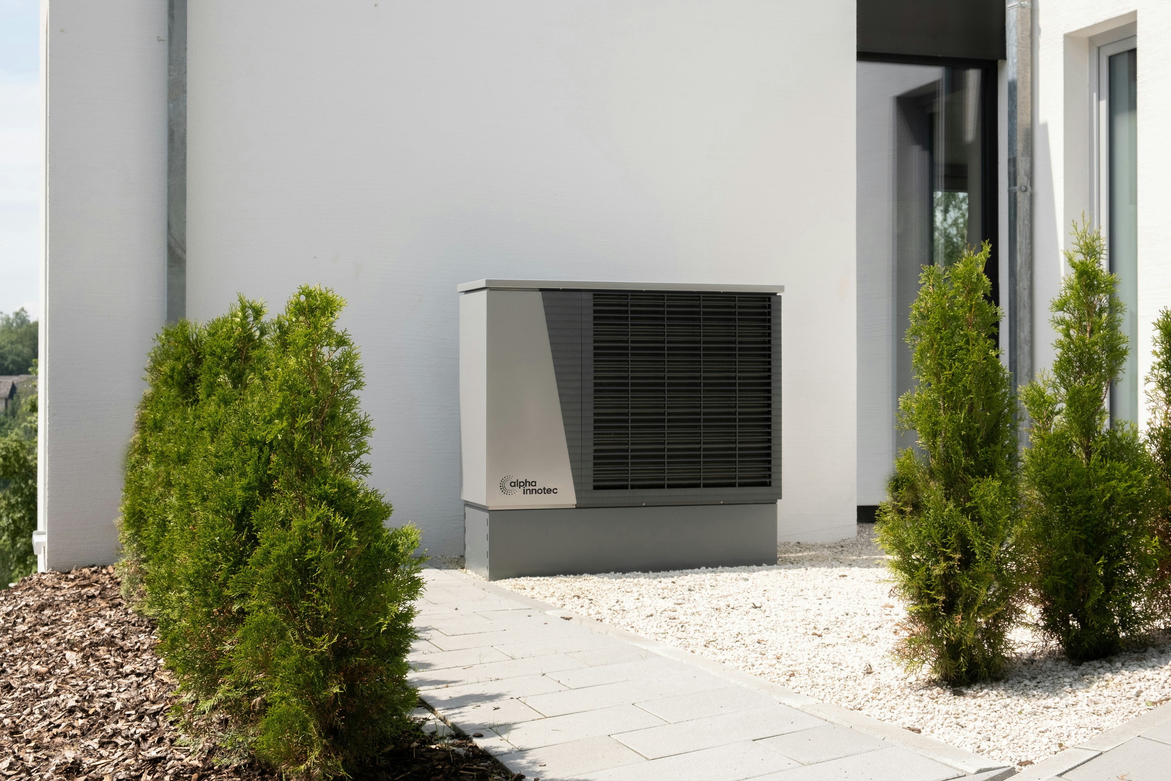 Modern heat pump system installed against home exterior with landscaping